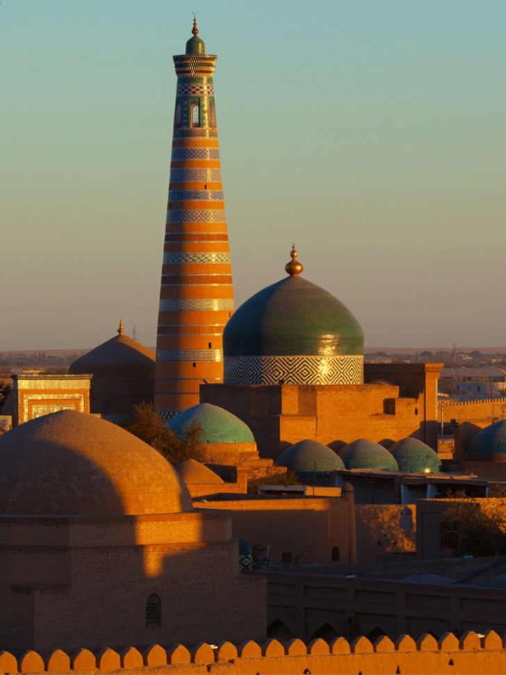 Kalta Minor Minaret and the domed skyline of Khiva's walled old city at golden hour