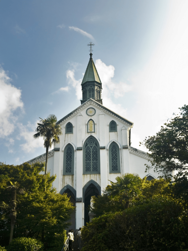 Oura Cathedral's white gothic facade and spire framed by palm trees