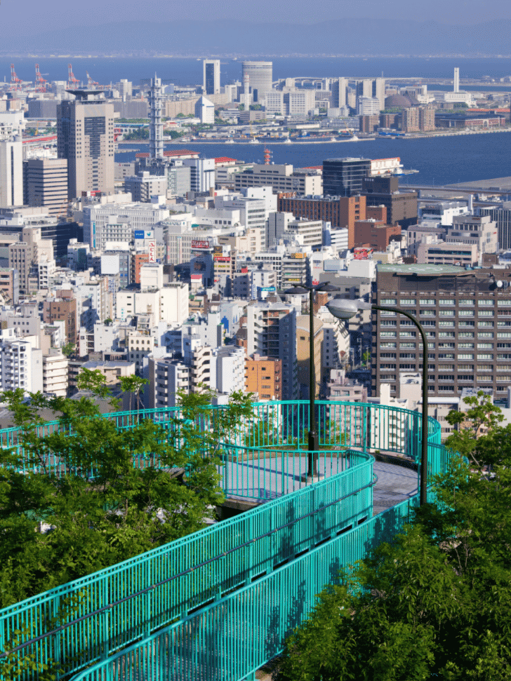 Turquoise spiral walkway overlooking Kobe's skyline and harbour from a hillside lookout