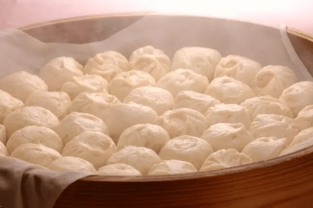 A bamboo steamer full of freshly steamed pork buns