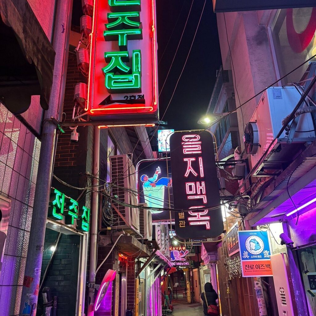 Neon Korean bar signs lighting up a narrow Euljiro back alley at night