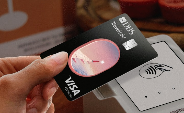 Hand tapping the DBS TravelLah! Visa debit card on a contactless payment terminal