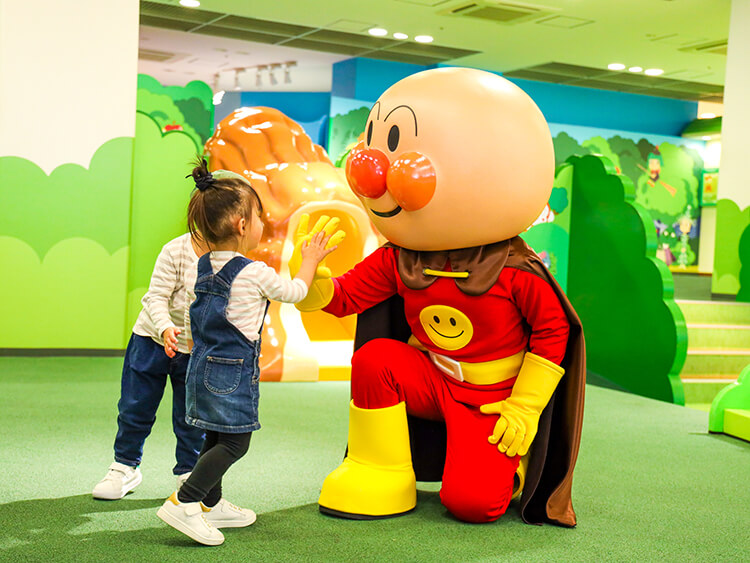 A toddler high-fiving the Anpanman mascot at the Kobe Anpanman Children's Museum