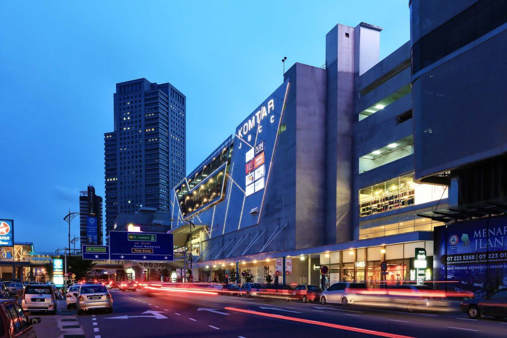 Komtar JBCC building exterior lit up at night, with traffic passing on the street below