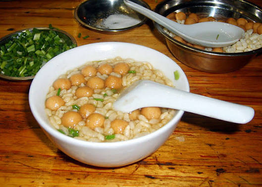 A bowl of Gongcheng oil tea topped with puffed rice and spring onion