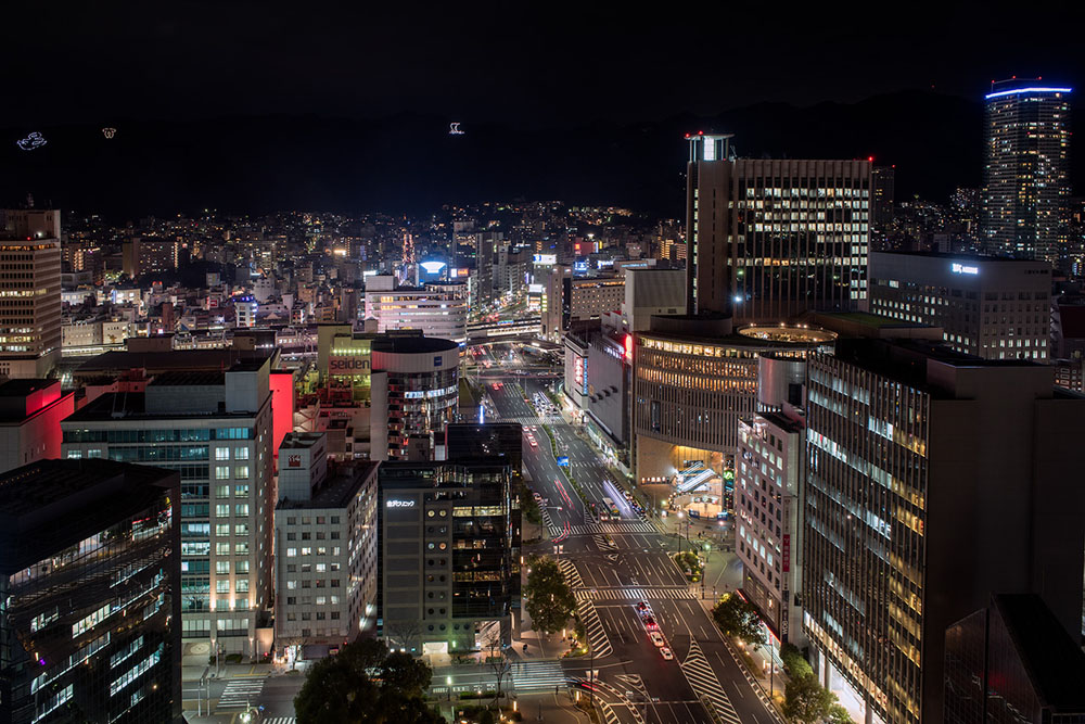 Kobe's illuminated street grid and buildings seen from an elevated night viewpoint