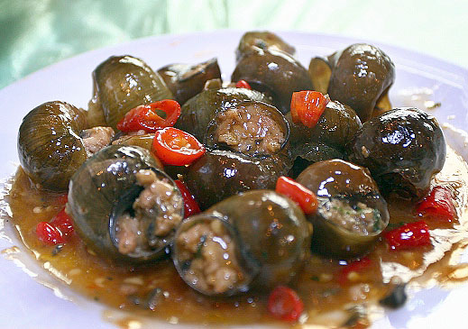 A plate of stuffed river snails in chilli sauce with sliced red chilli