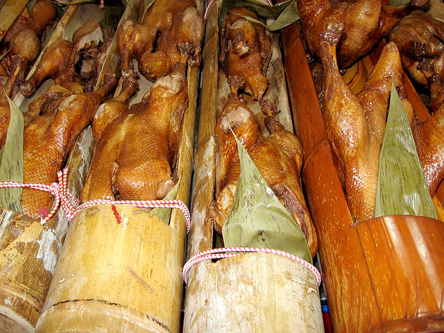 Whole roasted chickens packed into bamboo tubes lined with banana leaf