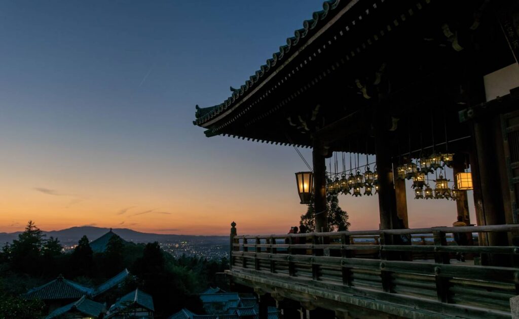 Sunset view over Nara city from the wooden balcony of Nigatsu-do Hall with lit lanterns
