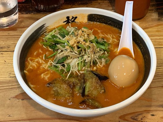 A bowl of Nagasaki tomato ramen topped with sauteed eggplant and a soft-boiled egg