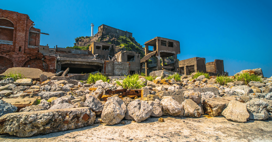 Rubble and collapsed concrete structures on Gunkanjima under a clear blue sky