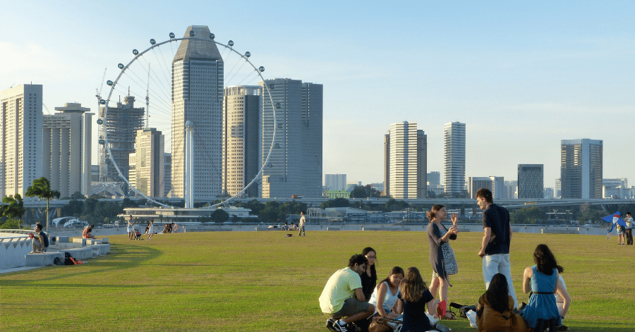 Marina Bay skyline with the Singapore Flyer, people relaxing on the grass in the foreground