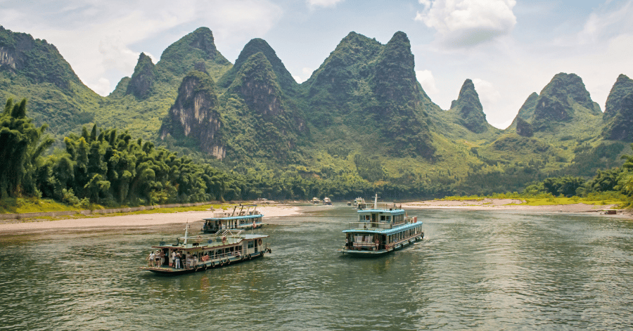 Two tour boats on the Li River passing beneath tall karst peaks