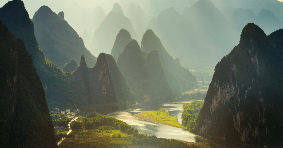 Rows of limestone karst peaks along the Li River lit gold at sunrise