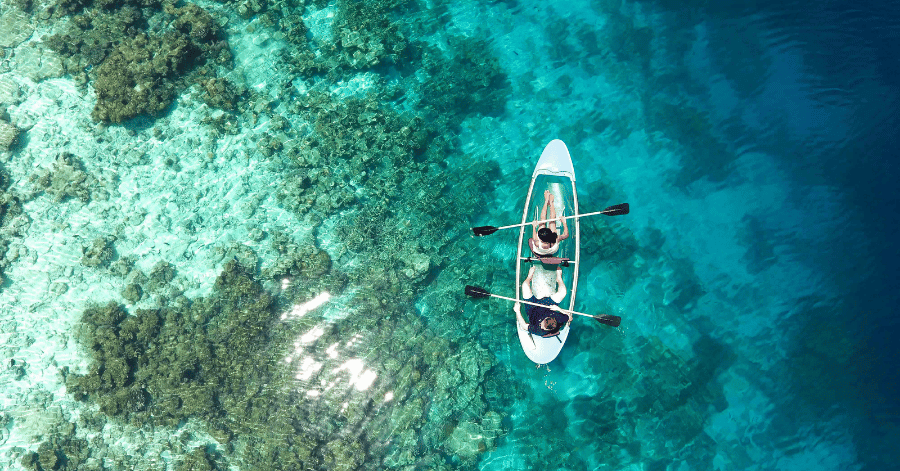Aerial view of two people kayaking over a shallow coral reef