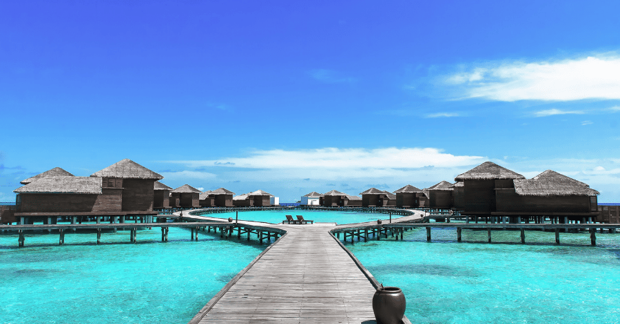 Overwater villas and a wooden walkway across a turquoise lagoon in the Maldives