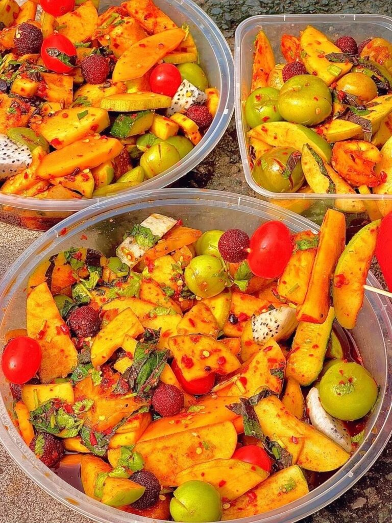 Bowls of pickled mango, tomato and green fruit tossed in chilli, a Guilin street snack