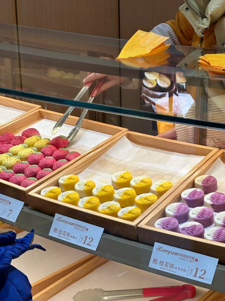 Colourful osmanthus cakes in a bakery display case, priced and labelled 桂花糕