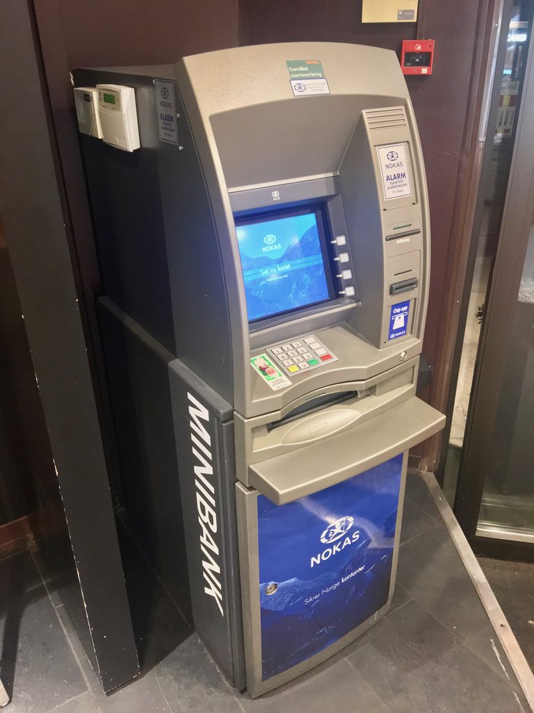 A grey Nokas ATM with the word MINIBANK down its side, inside a building