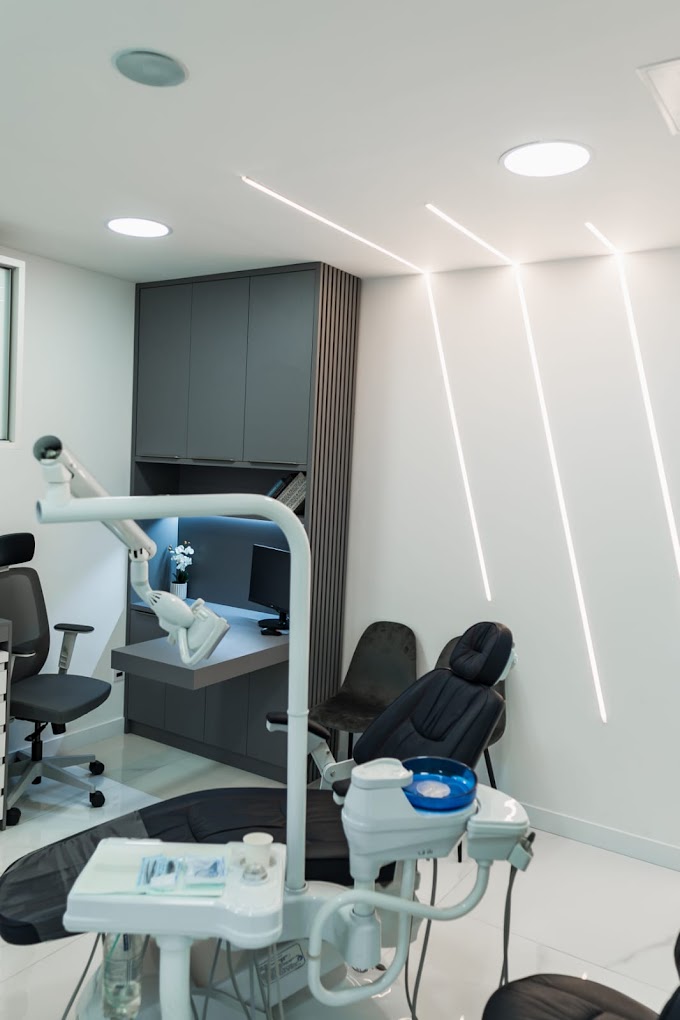 Bright treatment room at TAG Dental Clinic with a black dental chair, grey cabinets and LED strip lighting on the wall