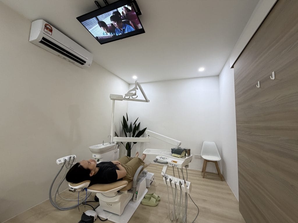 Treatment room at Ten Dental Clinic with a patient lying in the dental chair and a ceiling-mounted TV above