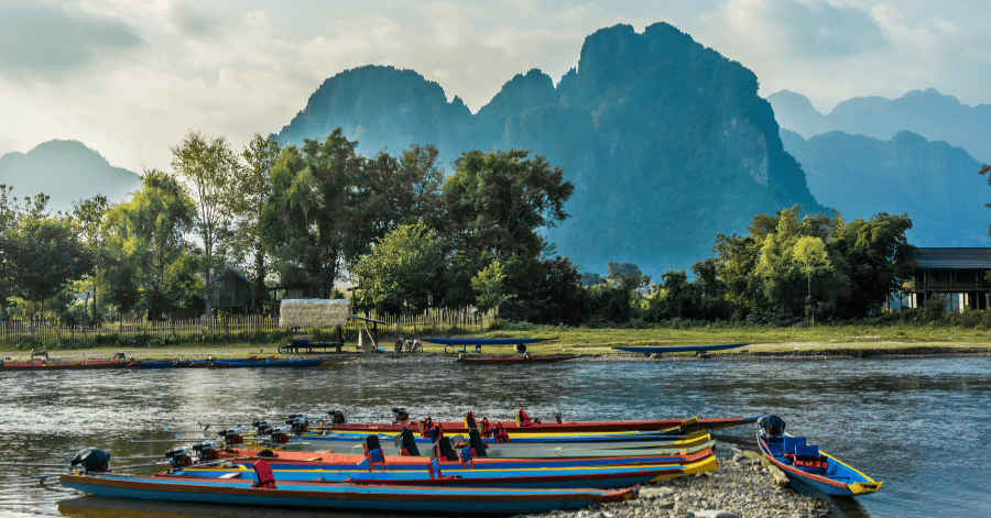 Longtail boats moored on the Nam Song River with limestone karst peaks rising behind Vang Vieng